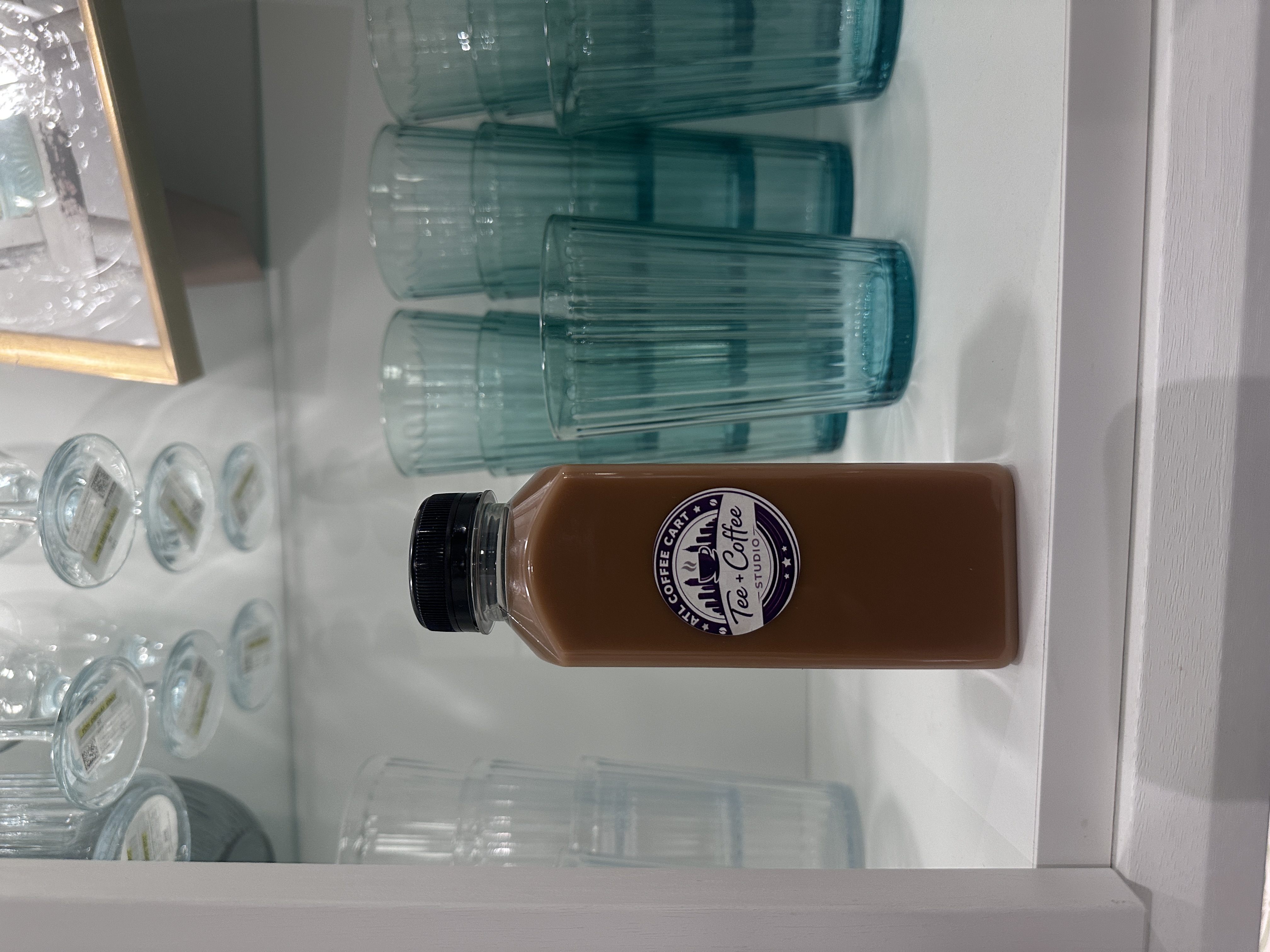 Tee Coffee Studio signature bottled iced latte displayed with teal glassware at Atlanta event