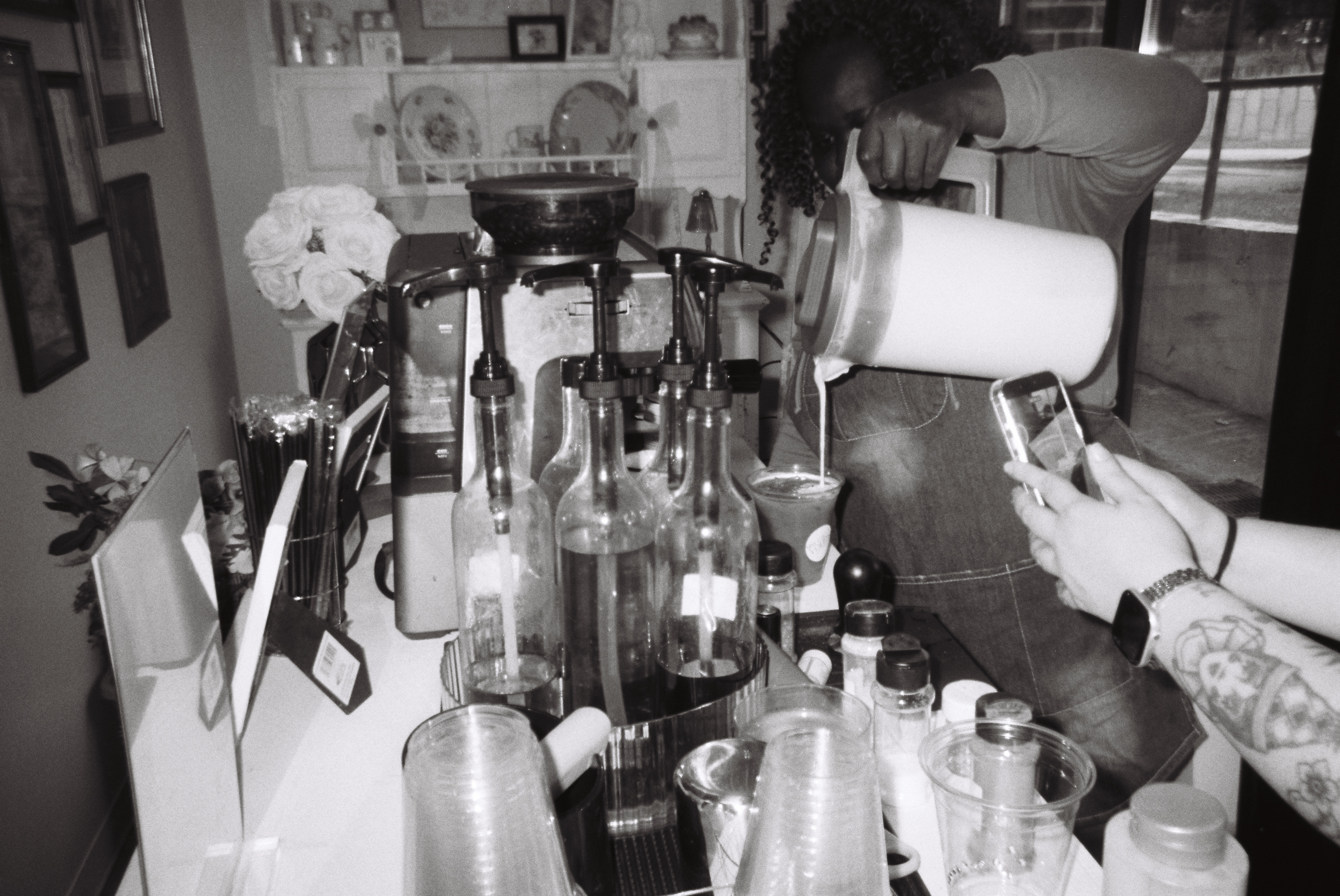 Black and white photo of Tee Coffee Studio barista pouring milk at espresso bar at Atlanta private event