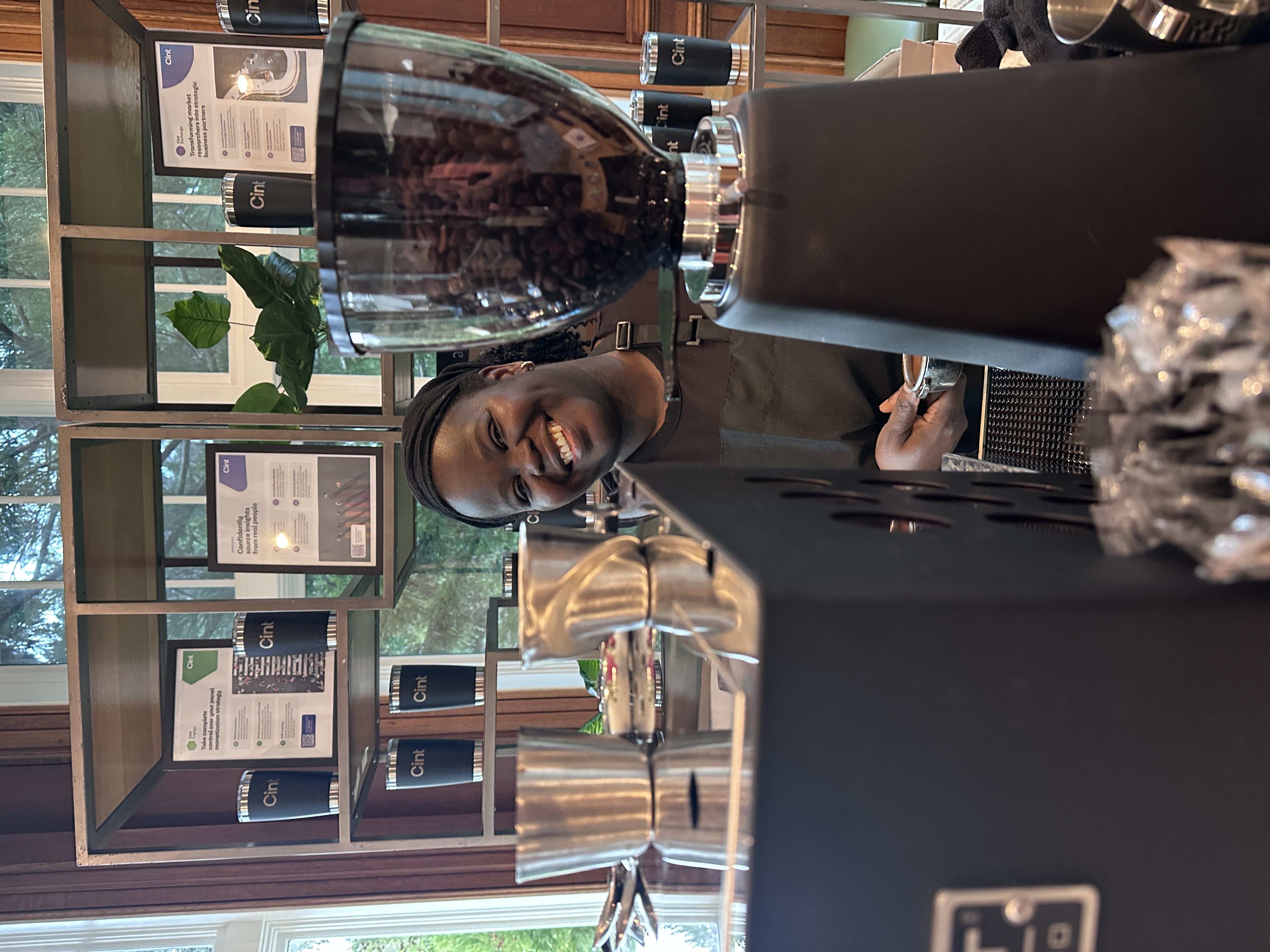 Tee Coffee Studio barista smiling through professional espresso grinder at Atlanta corporate event