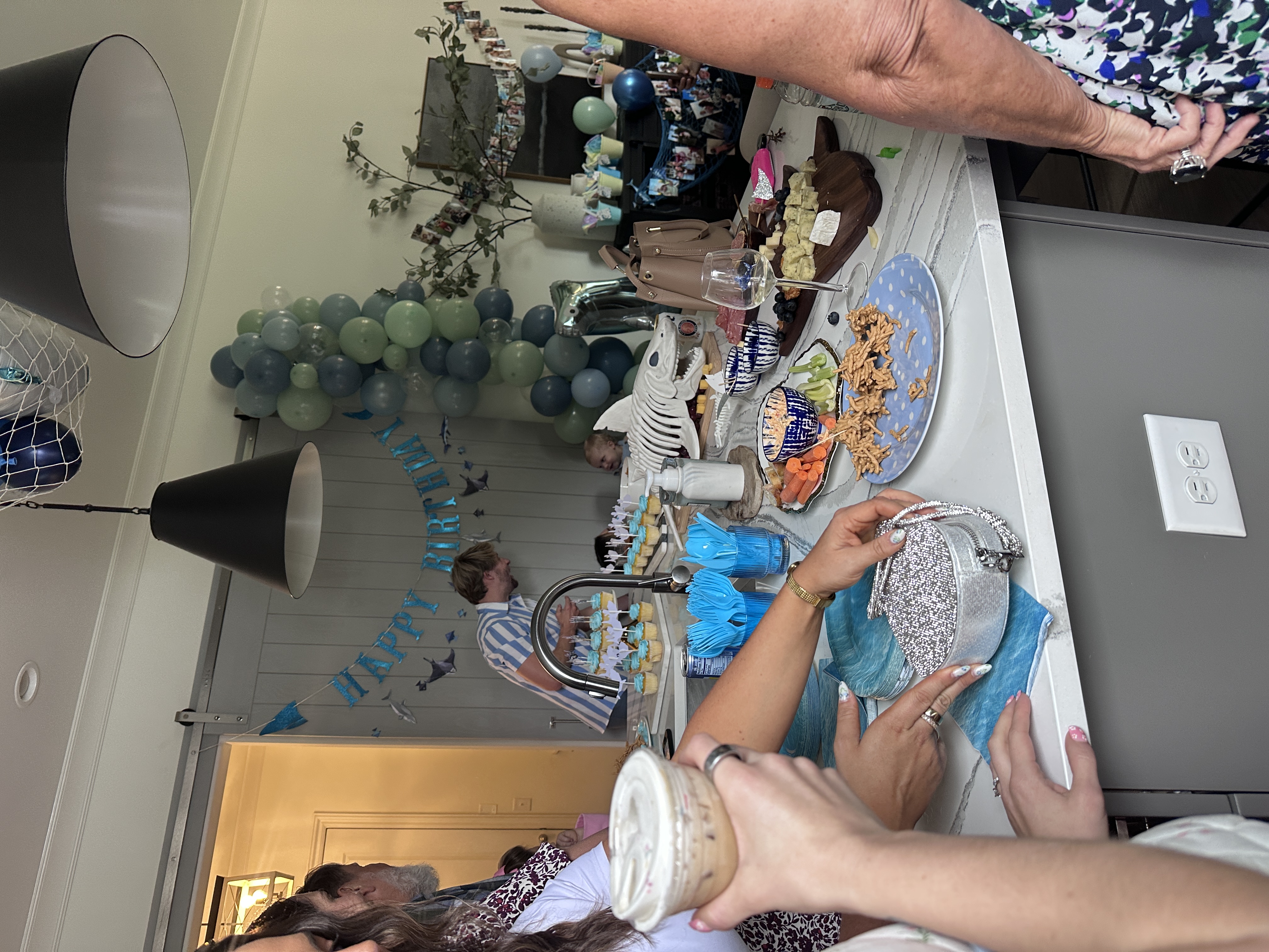 Indoor birthday party with balloon arch and guests holding Tee Coffee Studio specialty drinks Atlanta