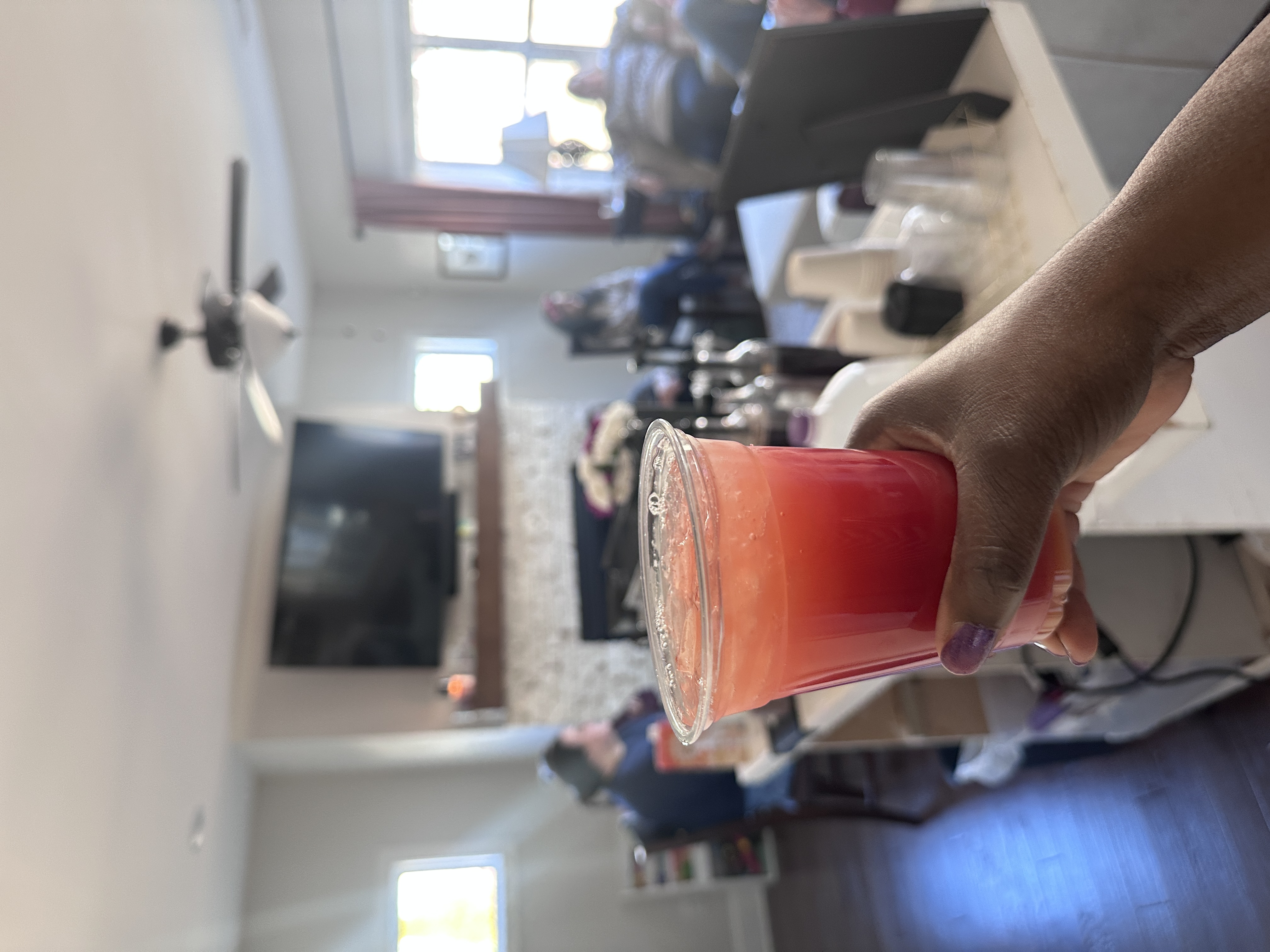 Tee Coffee Studio signature strawberry iced drink held up at Atlanta private gathering with guests in the background