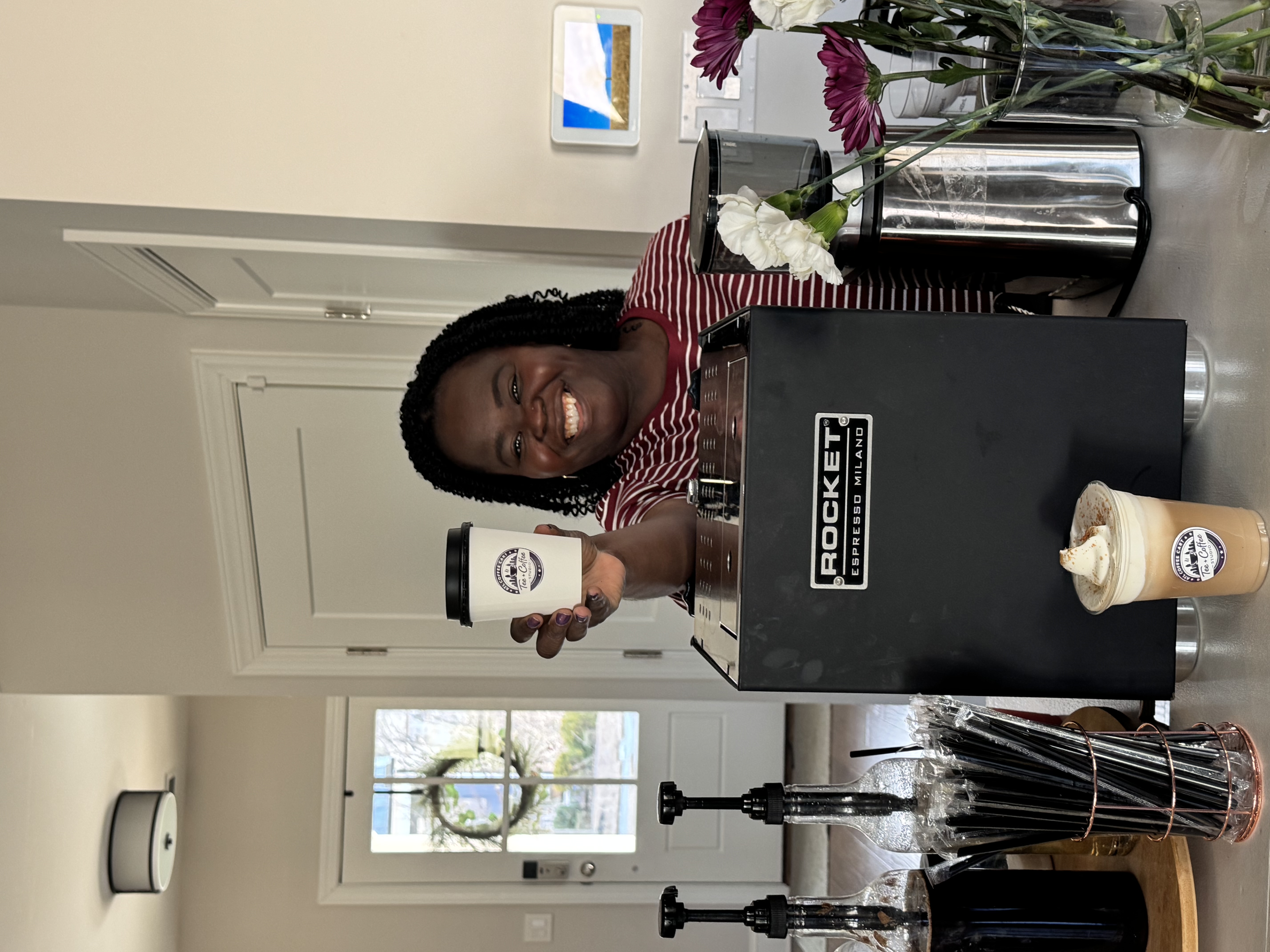 Tee George behind Tee Coffee Studio branded cart holding up a branded hot cup with Rocket espresso machine