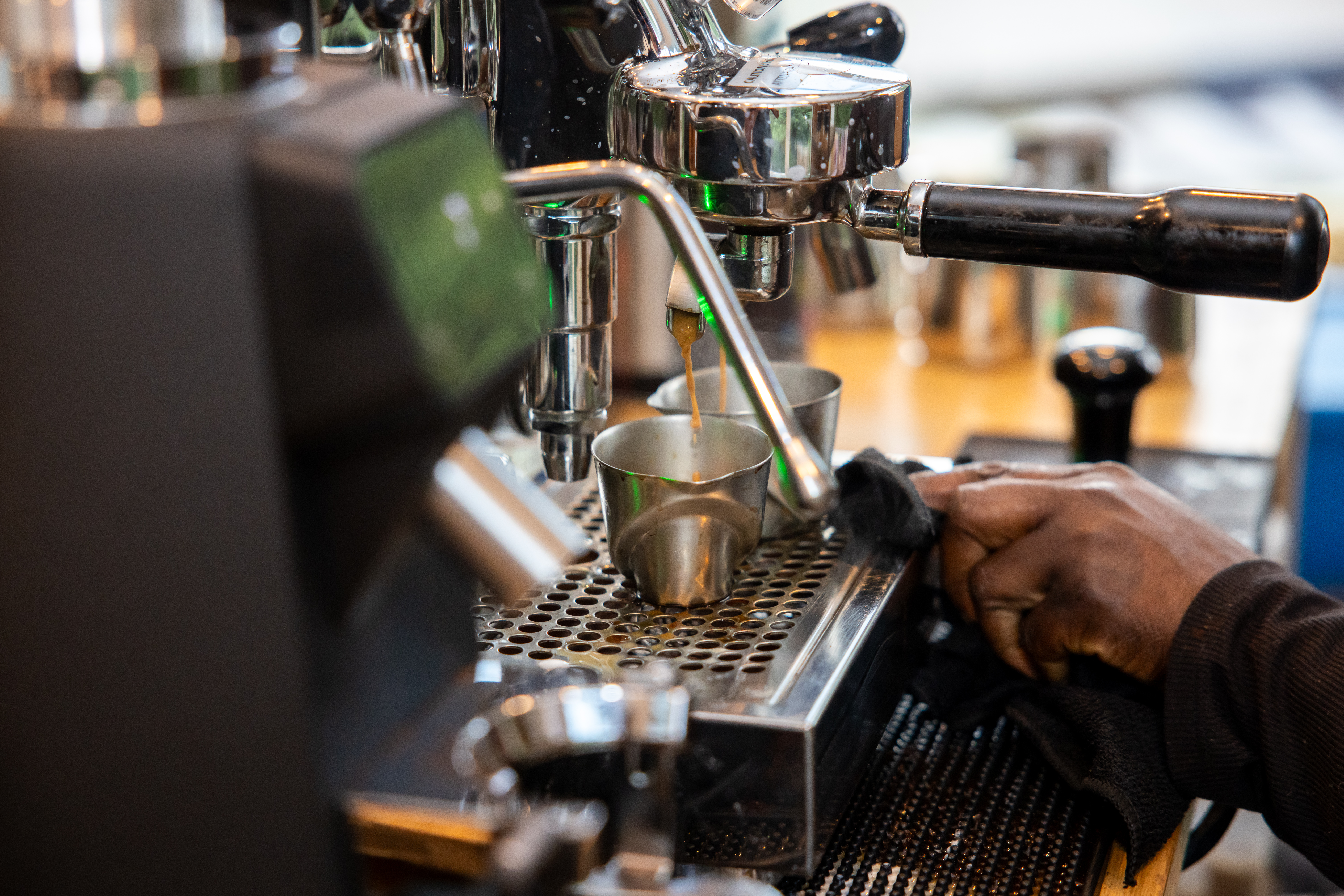 Espresso pulling from commercial machine portafilter into shot glasses at Tee Coffee Studio Atlanta event — macro craft photography