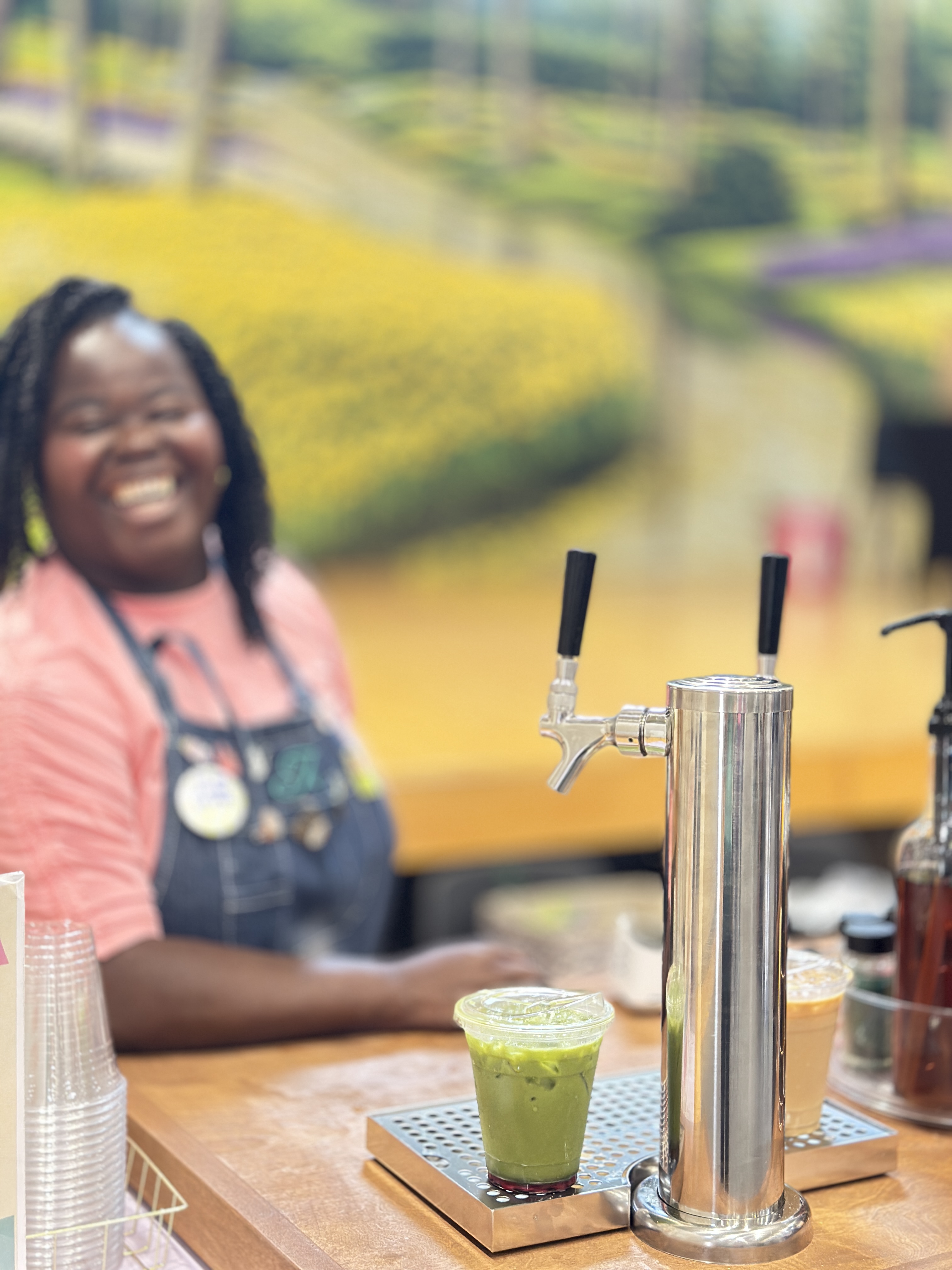 Smiling barista behind the Tee Coffee Studio tap cart with matcha drink at an Atlanta event