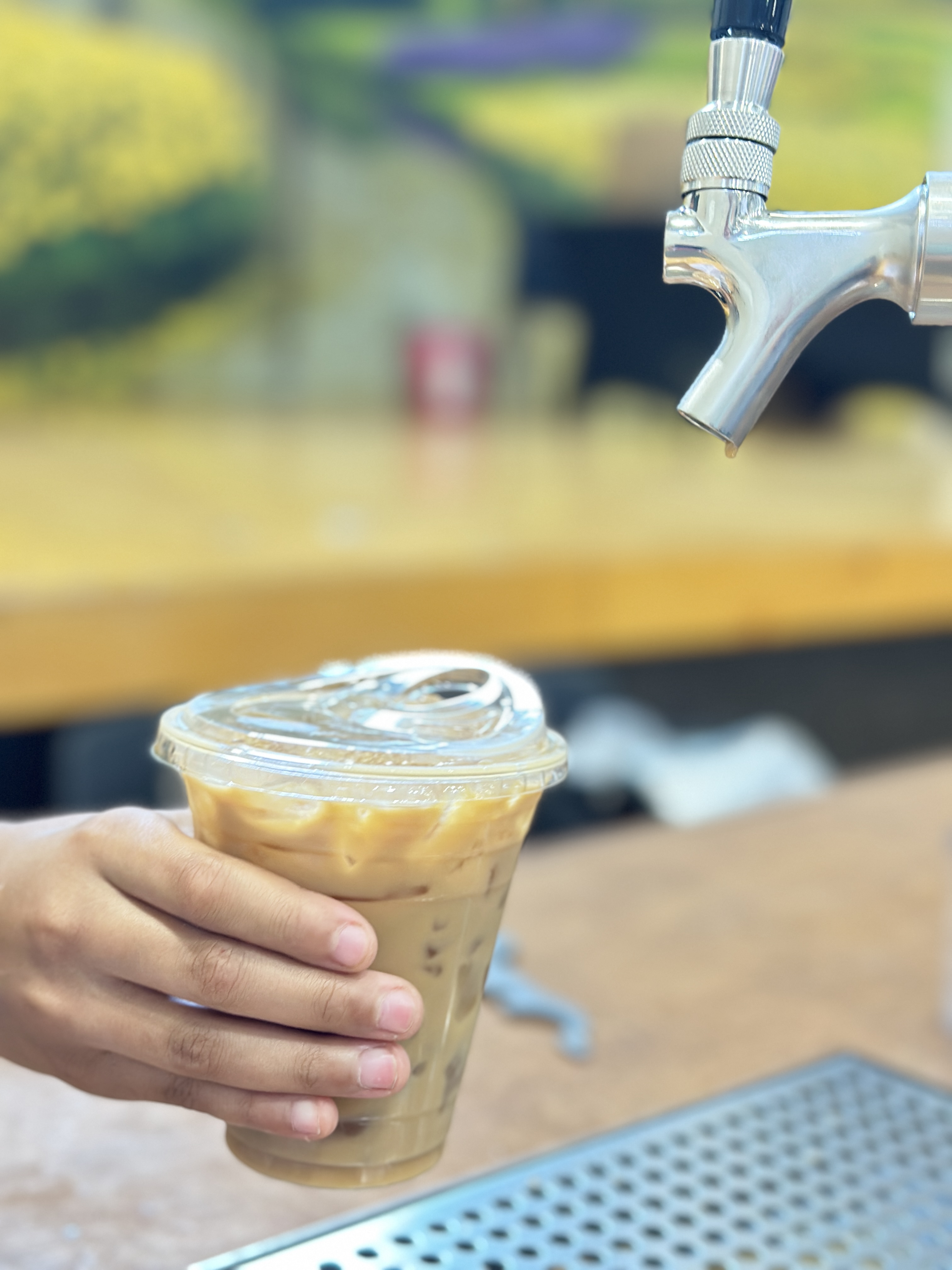 Cold brew latte being handed across the Tee Coffee Studio tap cart bar at an Atlanta event