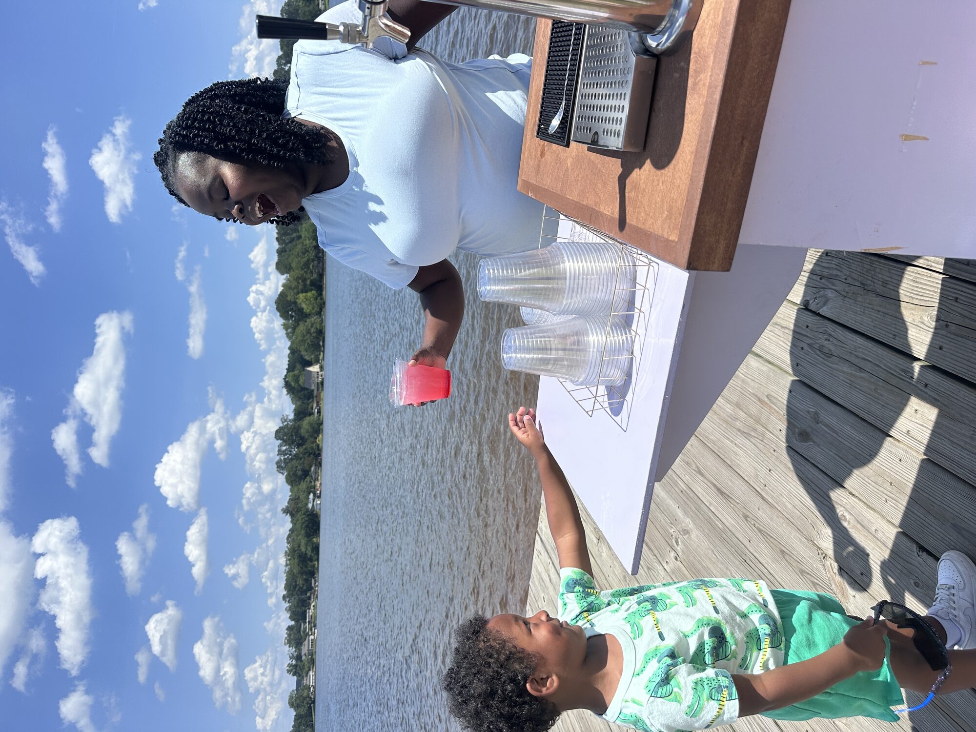 Young guest reaching for a pink drink handed across the Tee Coffee Studio tap cart at a lakeside Atlanta event