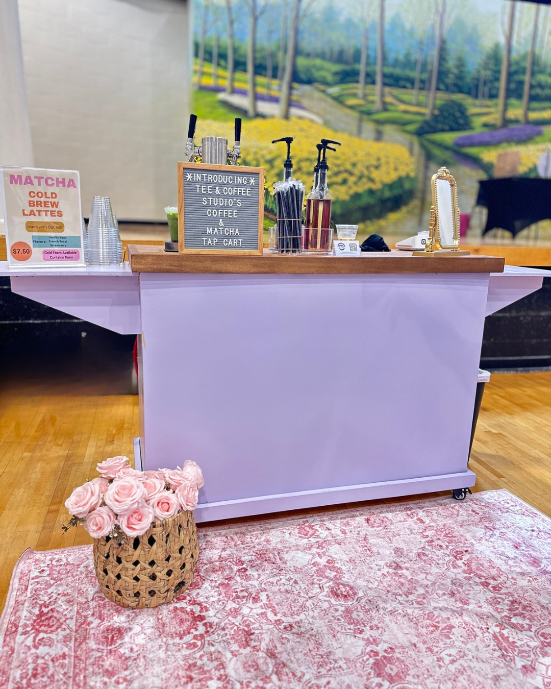 Tee Coffee Studio's lavender tap cart fully set up at an Atlanta event — dual tap system with branded signage and pink roses