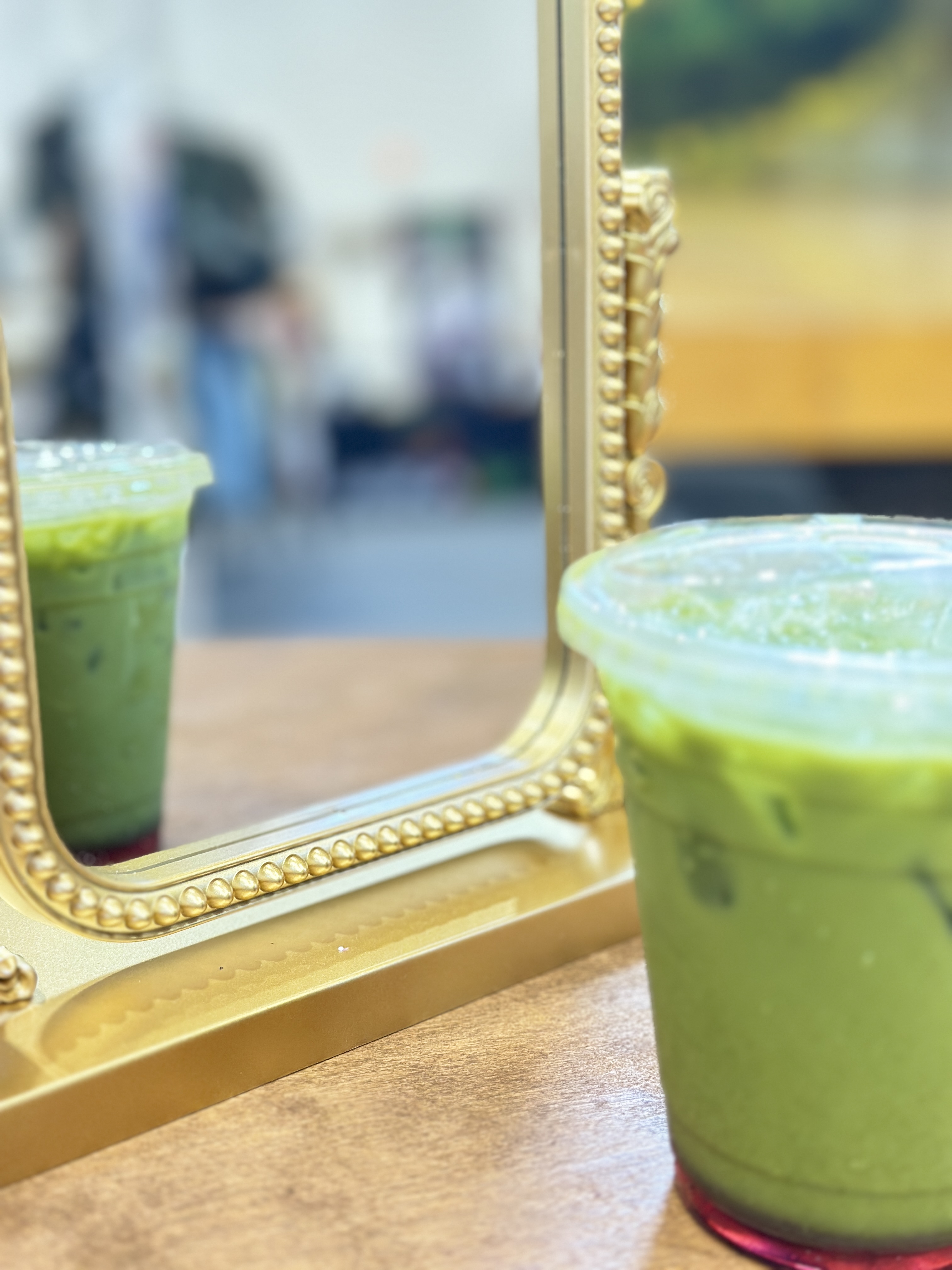 Iced matcha latte reflected in a gold mirror at Tee Coffee Studio tap cart event