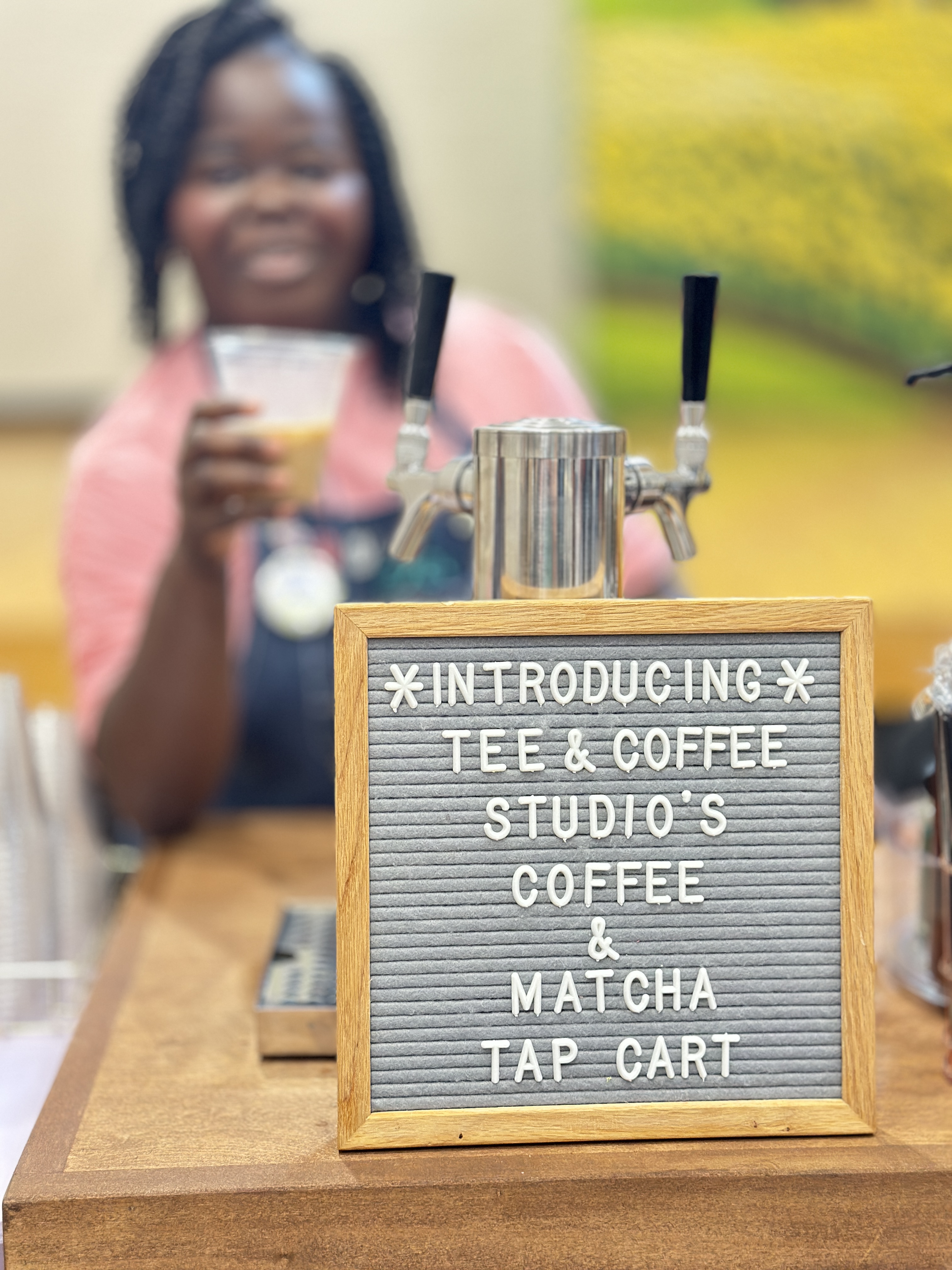 Tee Coffee Studio tap cart with smiling barista and letter board introducing the coffee and matcha tap cart
