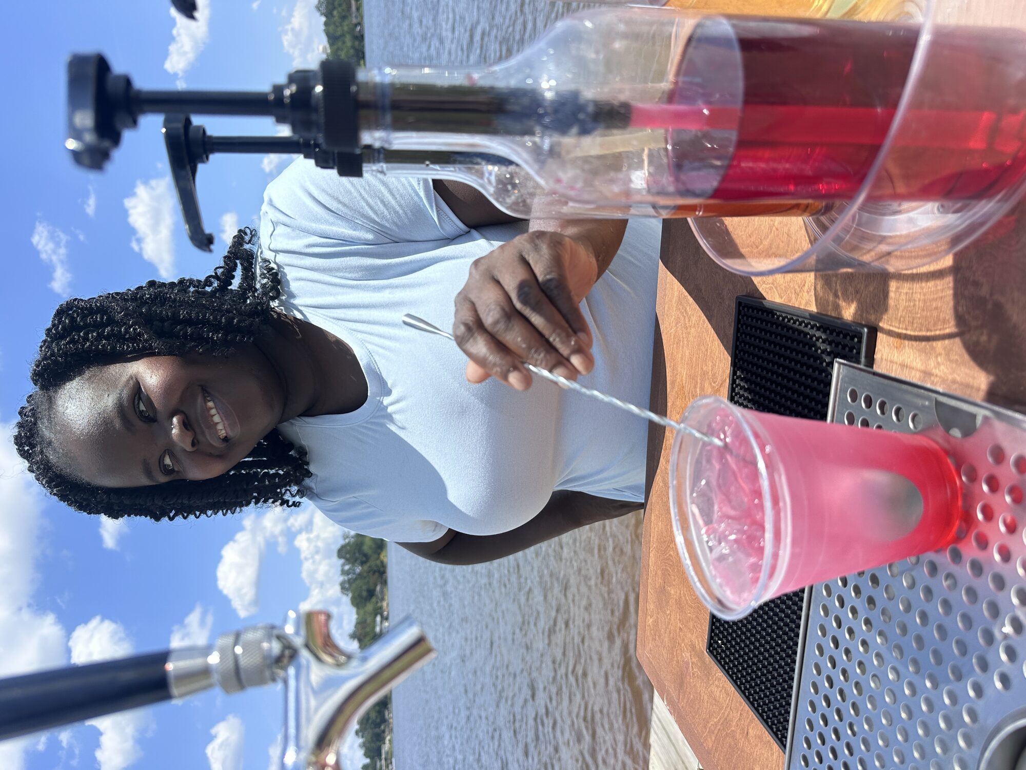 Tee Coffee Studio barista smiling while stirring a pink drink at a lakeside tap cart event